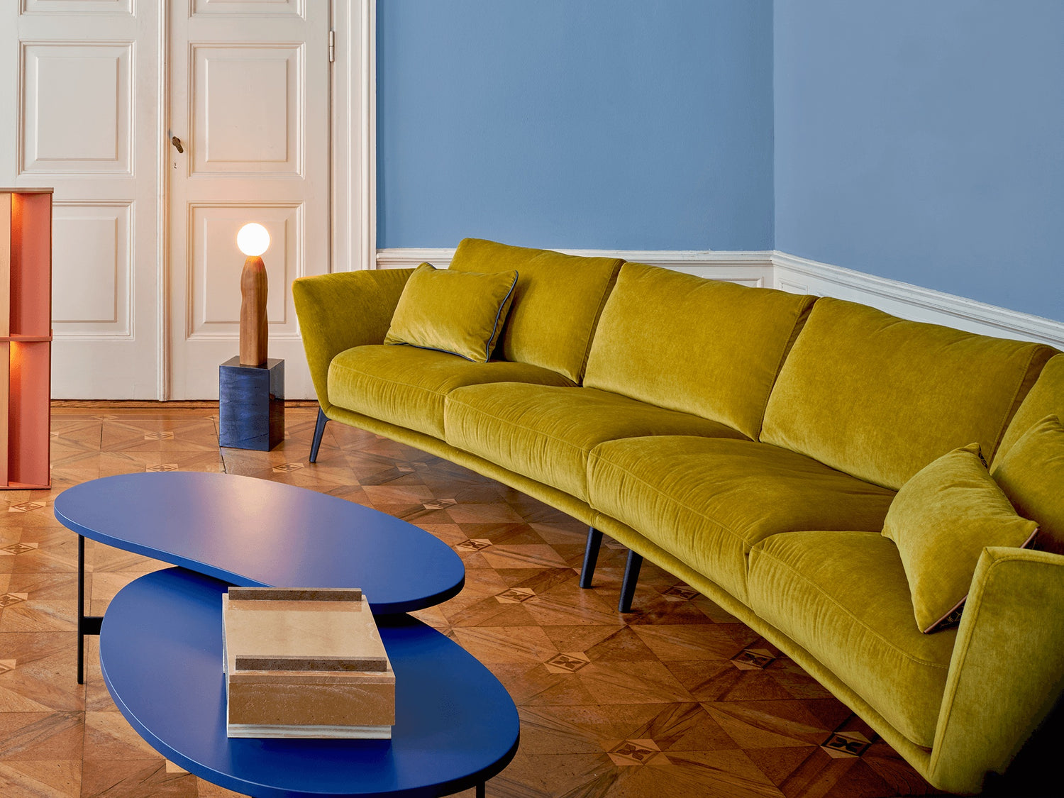 Leolux Rego Sofa in senfgelbem Samt im Altbau-Salon mit blauer Wand und Parkett
